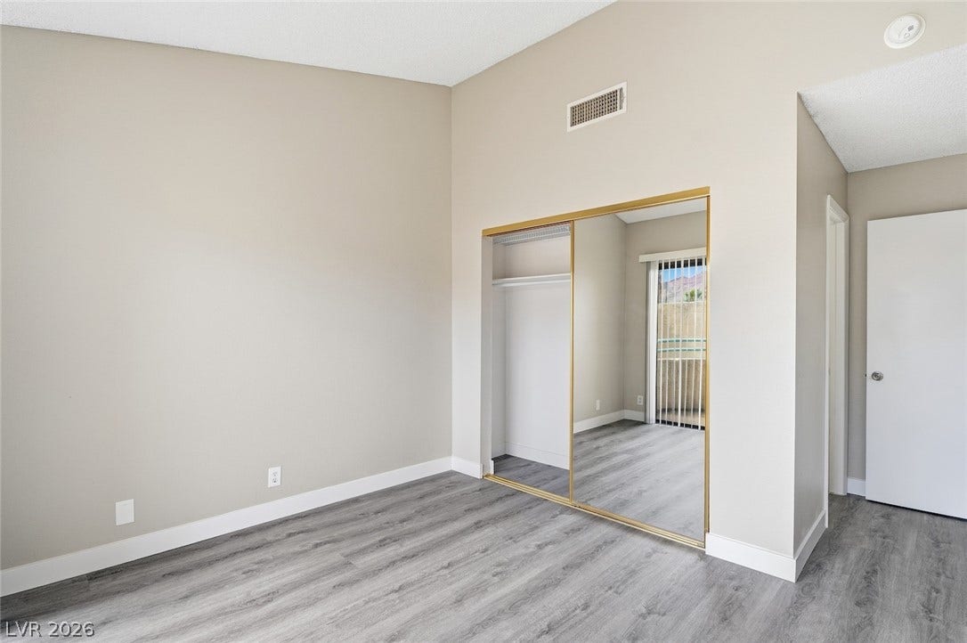 830 N Sloan Lane, #202, Las Vegas, NV 89110 High ceilings and durable wood-look flooring enhance this modern bedroom with mirrored closet doors.