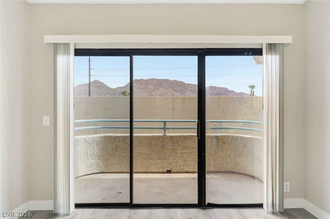 830 N Sloan Lane, #202, Las Vegas, NV 89110 Large sliding glass doors open to a private balcony showcasing distant mountain views.