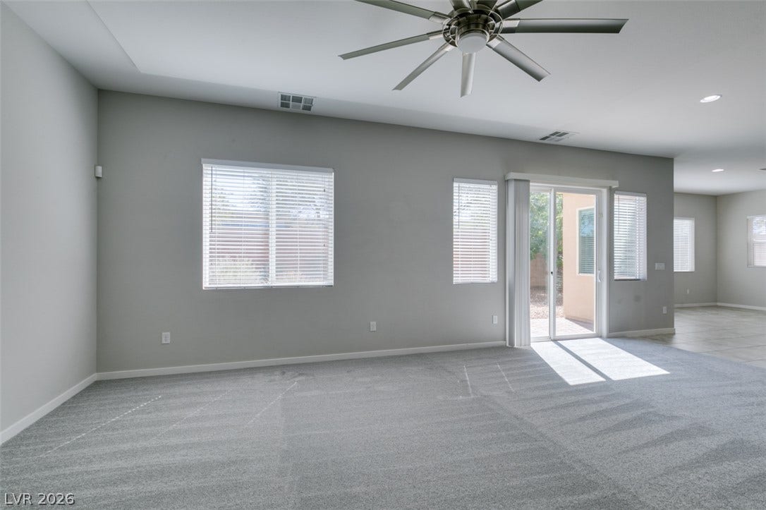 Plentiful natural light streams across this spacious, carpeted living area through sliding glass doors.