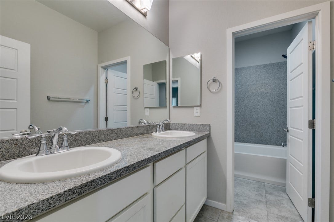 A stone-countertop double vanity sits adjacent to a separate tub and shower area.
