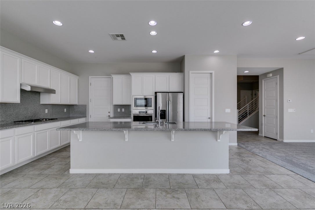 An open kitchen layout boasts granite countertops, tile flooring, and integrated stainless steel appliances.