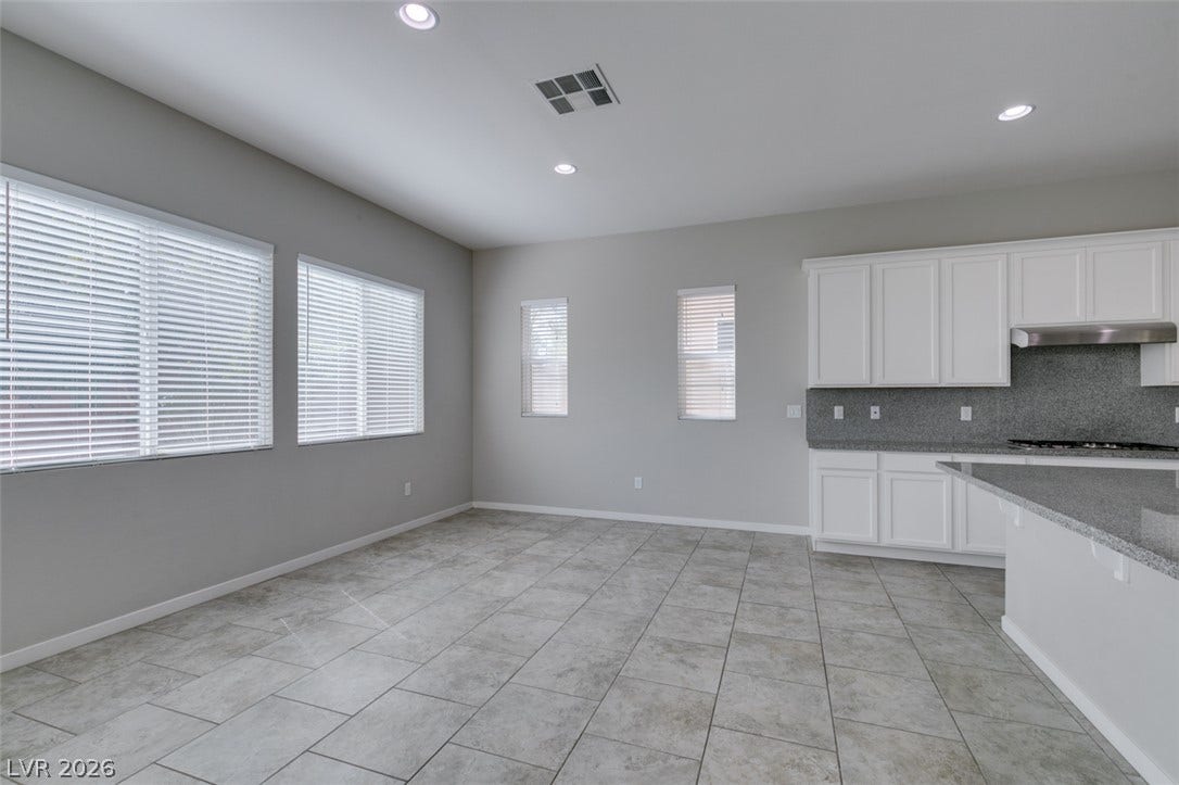 Tiled flooring and recessed lighting accent this versatile dining space adjacent to the kitchen.