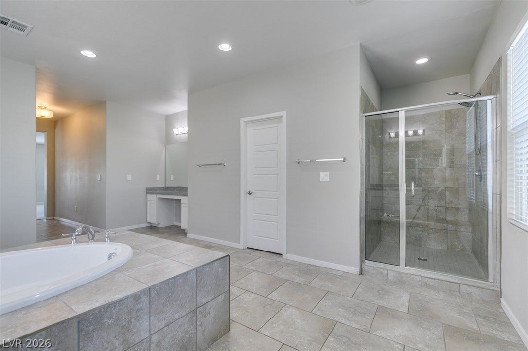 Tiled floors and a separate walk-in shower define this spacious primary bath.