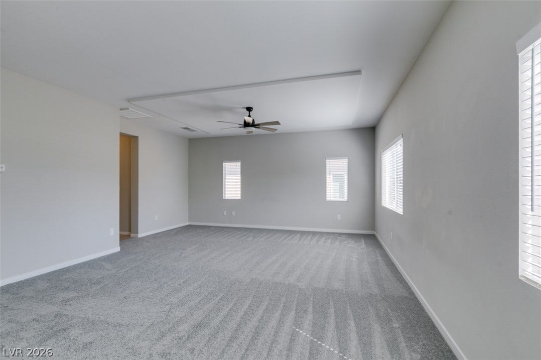 Plush carpeting and a classic tray ceiling elevate this versatile living space.
