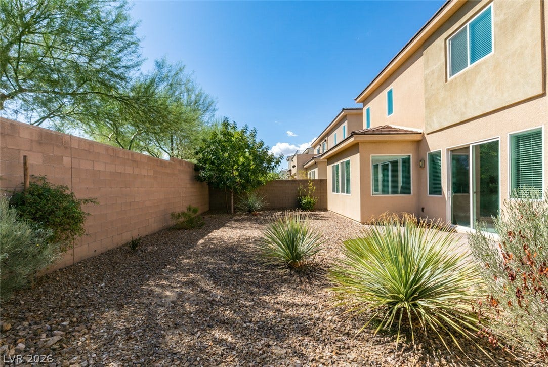 A low-maintenance gravel yard with desert plantings is enclosed by a privacy block wall.