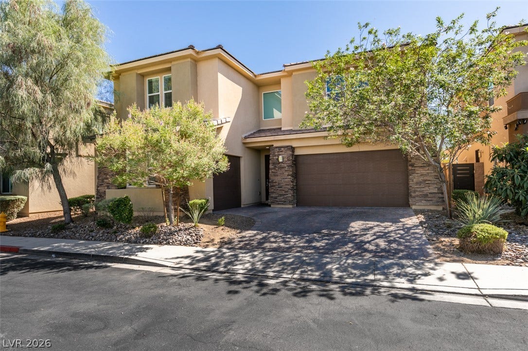Stone accents and manicured desert landscaping frame the welcoming exterior of this multi-level home.