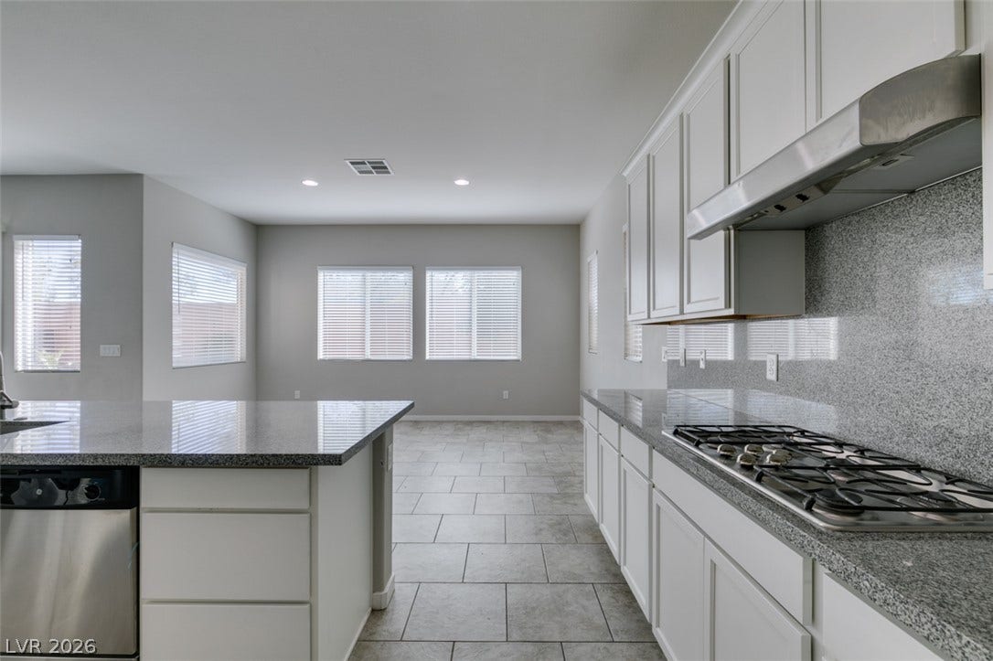 Polished stone countertops pair beautifully with tile flooring in this modern, airy kitchen.