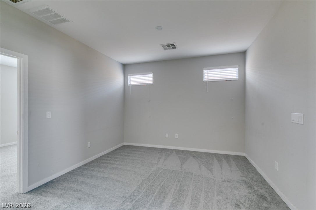 Plush wall-to-wall carpeting and high transom windows define this versatile secondary bedroom space.