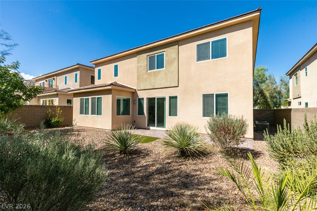 Low-maintenance desert landscaping frames the stucco exterior of this multi-level home under clear blue skies.