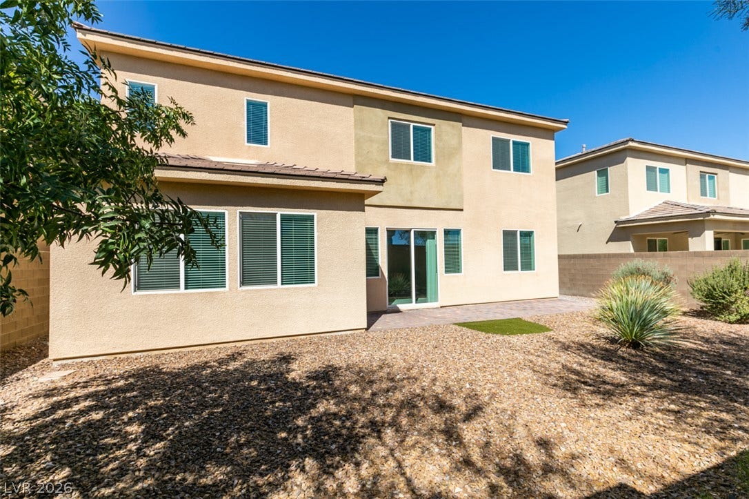 A spacious backyard with low-maintenance desert landscaping frames the stucco exterior.