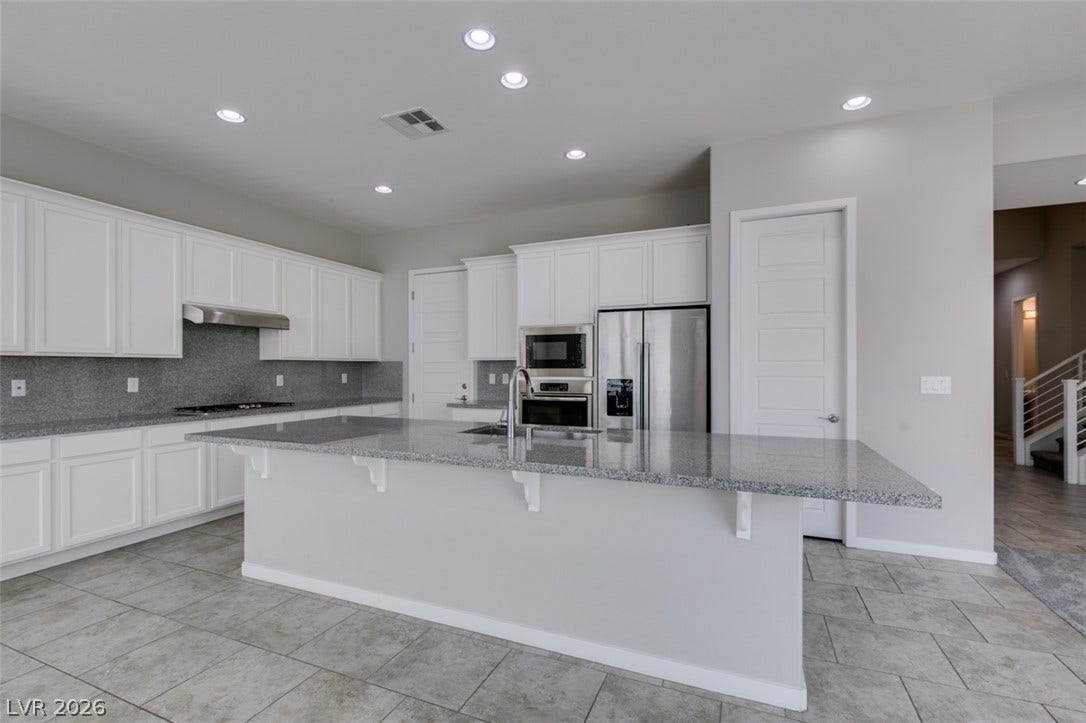Polished granite countertops and classic white cabinetry define this beautifully appointed kitchen space.