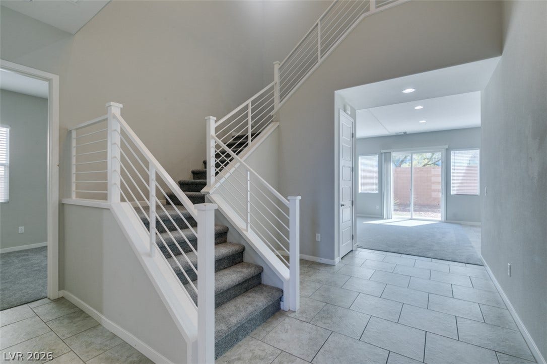 An inviting entrance foyer introduces tiled floors and a carpeted staircase with modern railings.