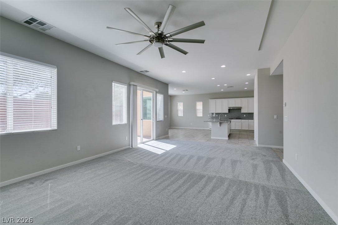 An open floor plan connects the carpeted living area to a modern kitchen.