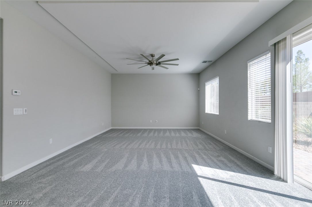 Plentiful natural light streams across carpeted flooring through wide sliding doors.