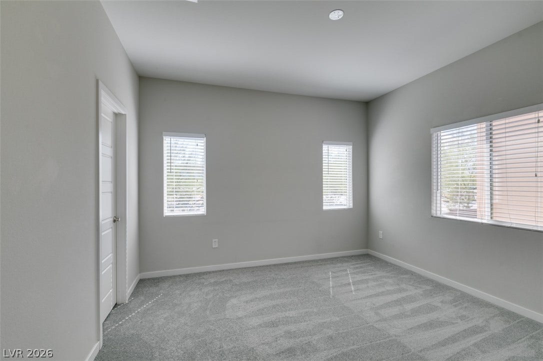 Plush carpeting anchors this versatile room under high ceilings and abundant natural light.