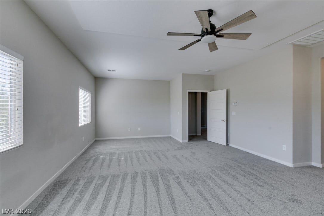 An airy bedroom features soft carpeting, generous window lighting, and clean contemporary lines.