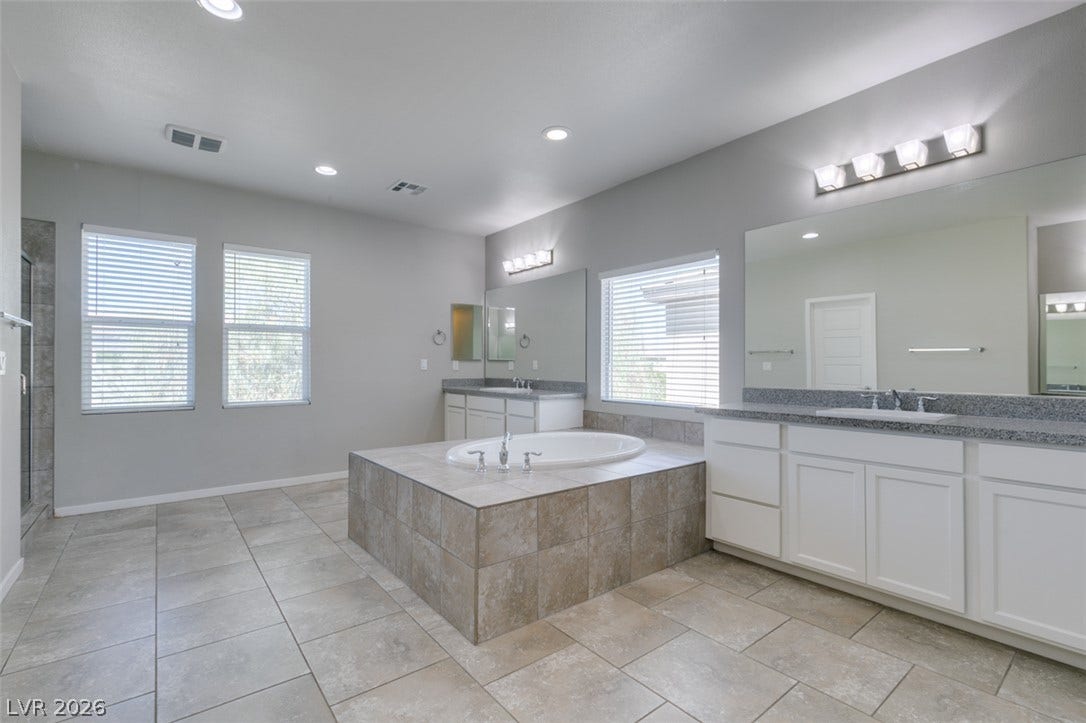 Tiled flooring and a raised soaking tub anchor this generously scaled bathroom retreat.