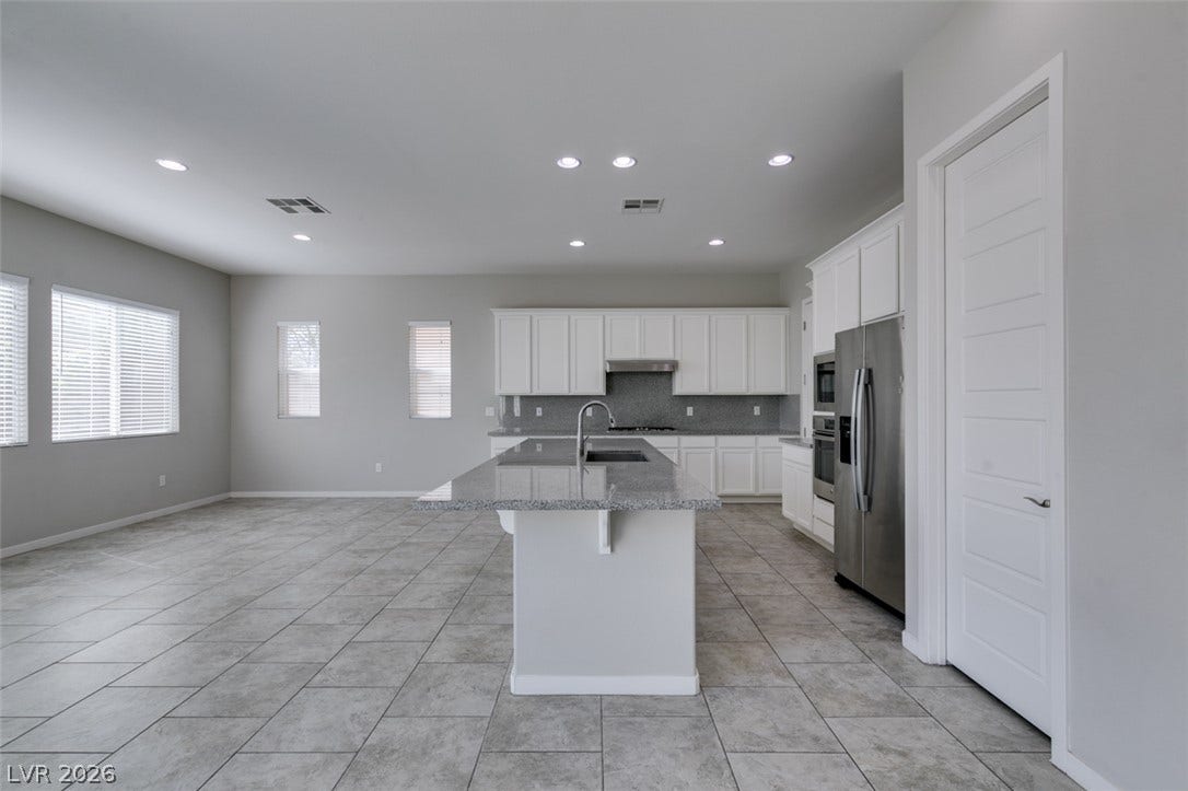 Polished tile flooring and granite counters define this expansive open kitchen layout.