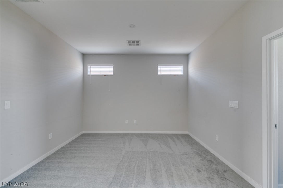 Crisp neutral walls and soft carpeting define this versatile bonus room with high clerestory windows.