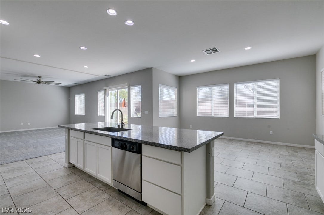 An open floorplan seamlessly connects the stone-countertop kitchen island to adjacent living spaces.