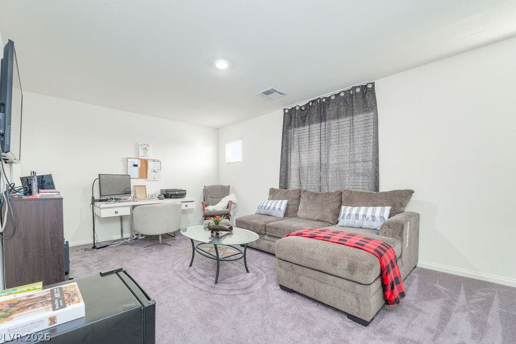 6135 Larimar Gold Street, North Las Vegas, NV 89115 Plush carpeting anchors this versatile living space featuring recessed lighting and tall windows.