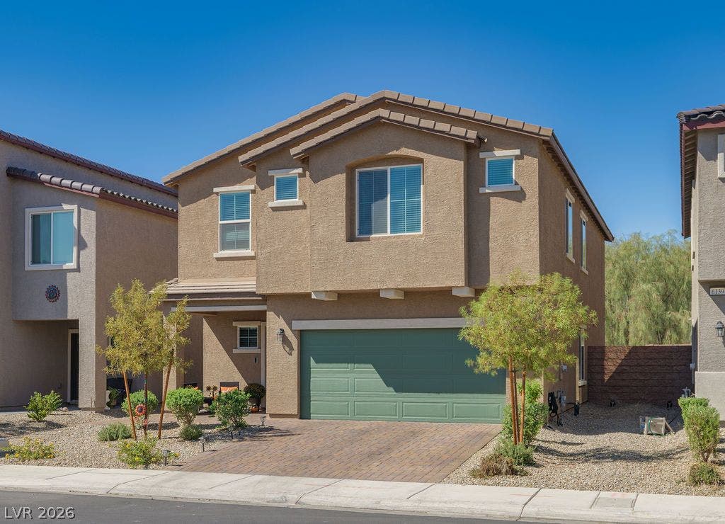 6135 Larimar Gold Street, North Las Vegas, NV 89115 A paved driveway leads to the integrated garage of this modern multi-level suburban residence.
