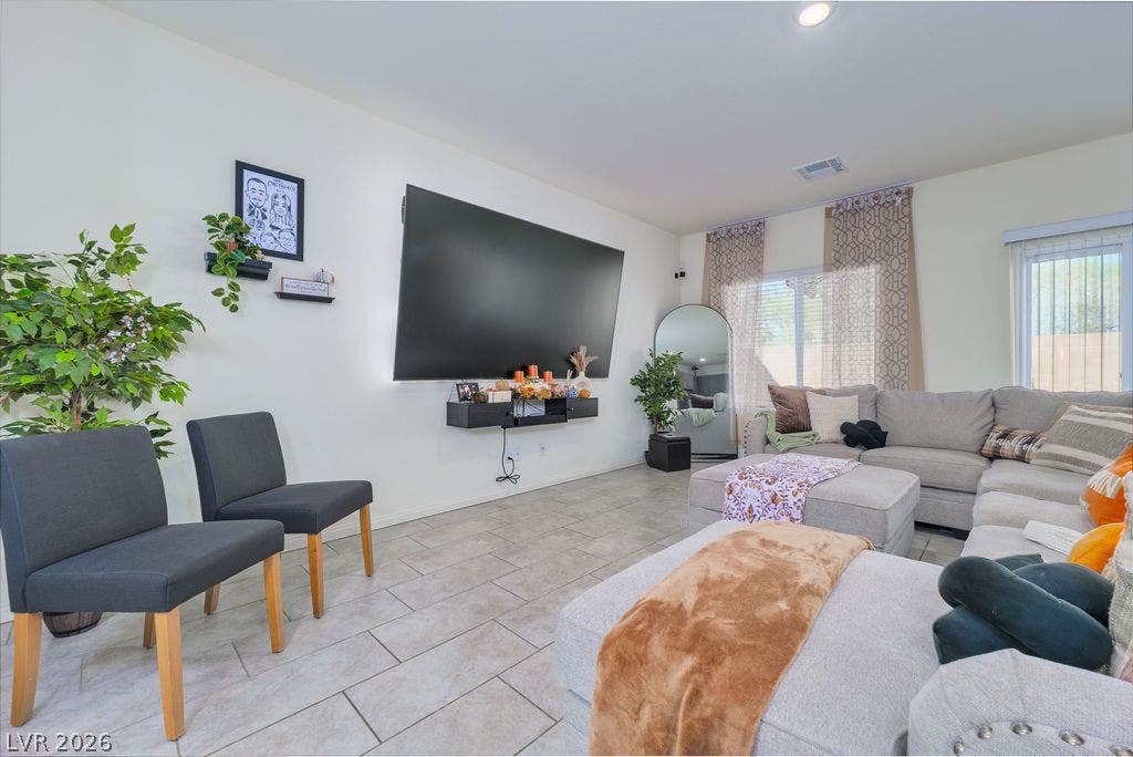 6135 Larimar Gold Street, North Las Vegas, NV 89115 Durable tile flooring highlights this comfortable, modern living room setup with large windows.