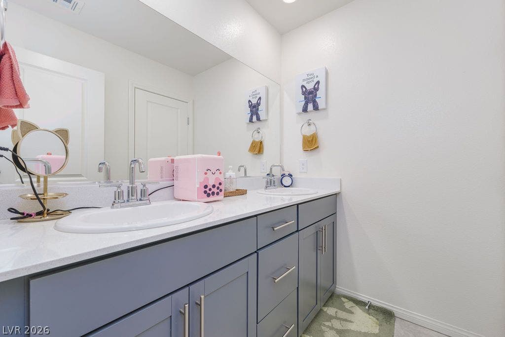 6135 Larimar Gold Street, North Las Vegas, NV 89115 Double sinks with chrome fixtures pair perfectly with quartz countertops and spacious under-vanity storage.