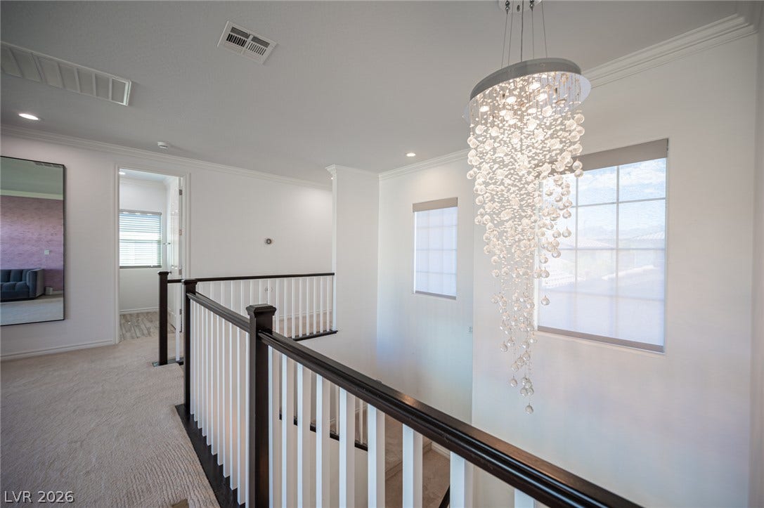 322 Elder View Drive, Las Vegas, NV 89138 Crisp white walls, plush carpeting, and elegant crown molding frame this bright upstairs landing.
