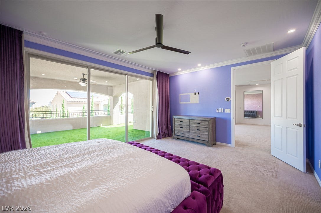 322 Elder View Drive, Las Vegas, NV 89138 Glass sliding doors open to a private balcony, filling this carpeted bedroom with natural light.