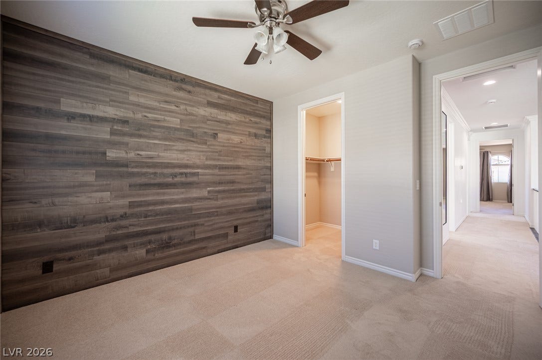 322 Elder View Drive, Las Vegas, NV 89138 Plush carpeting and a rich wood-plank accent wall define this comfortable bedroom space.