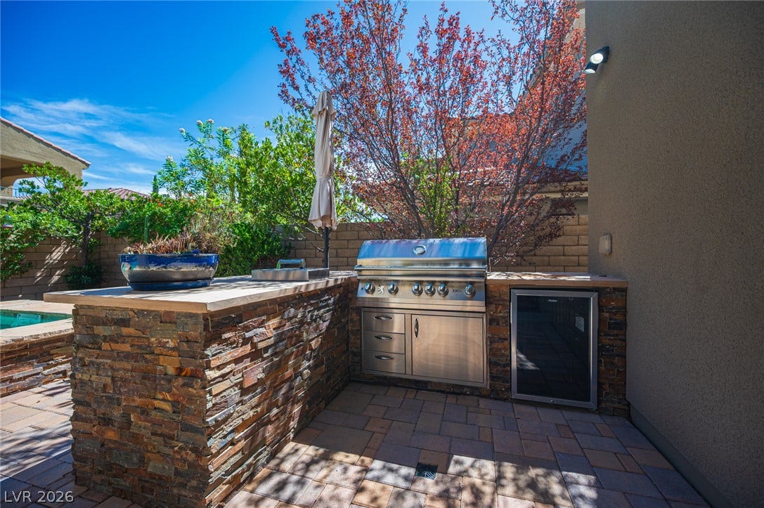 322 Elder View Drive, Las Vegas, NV 89138 An outdoor kitchen features a built-in stone grill station set on a paved patio.