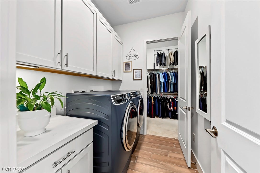 Ample cabinetry and durable wood-look flooring maximize function in this modern laundry space.