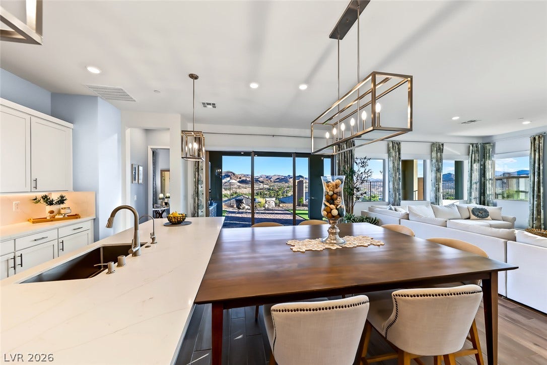 An open floorplan seamlessly connects the stone counters of this kitchen to the living area.