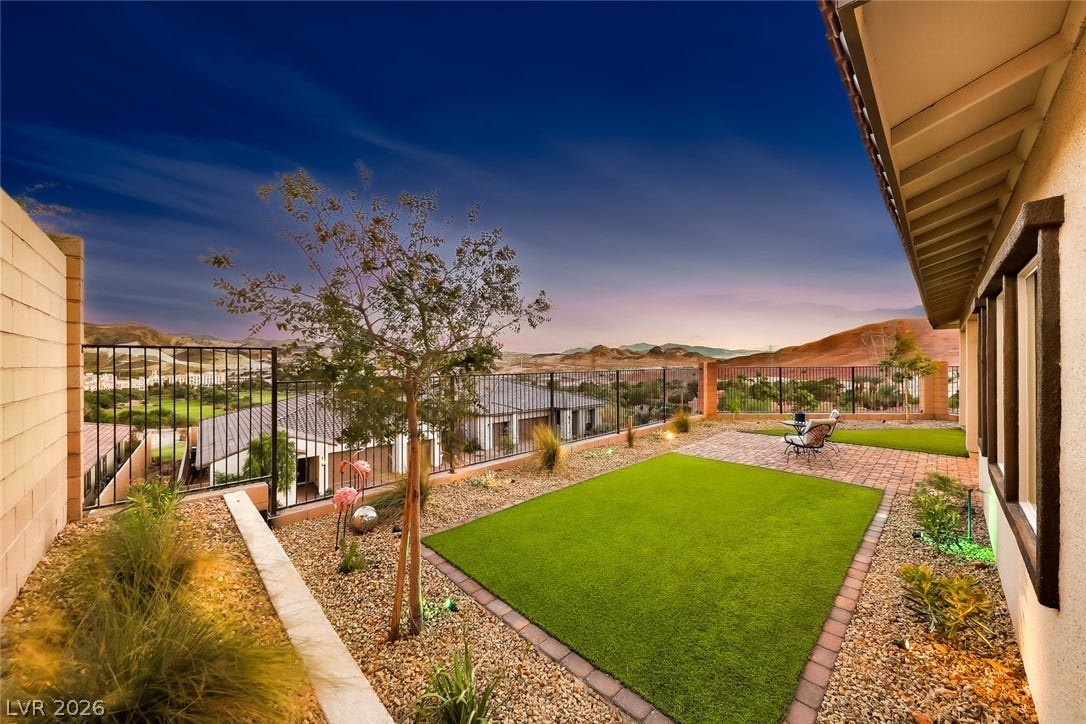 A neatly manicured lawn and stone patio look out over panoramic mountain views.