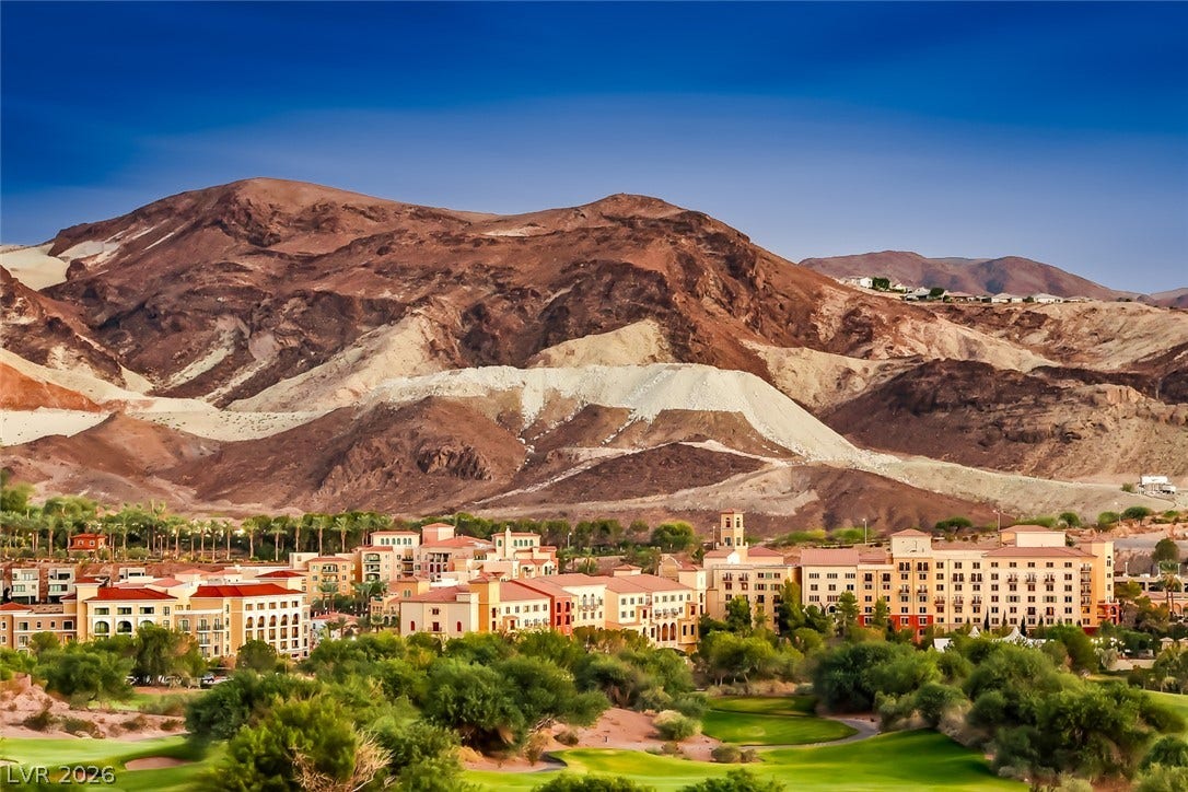 Dramatic mountain peaks rise sharply behind a nestled resort community surrounded by lush greenery.