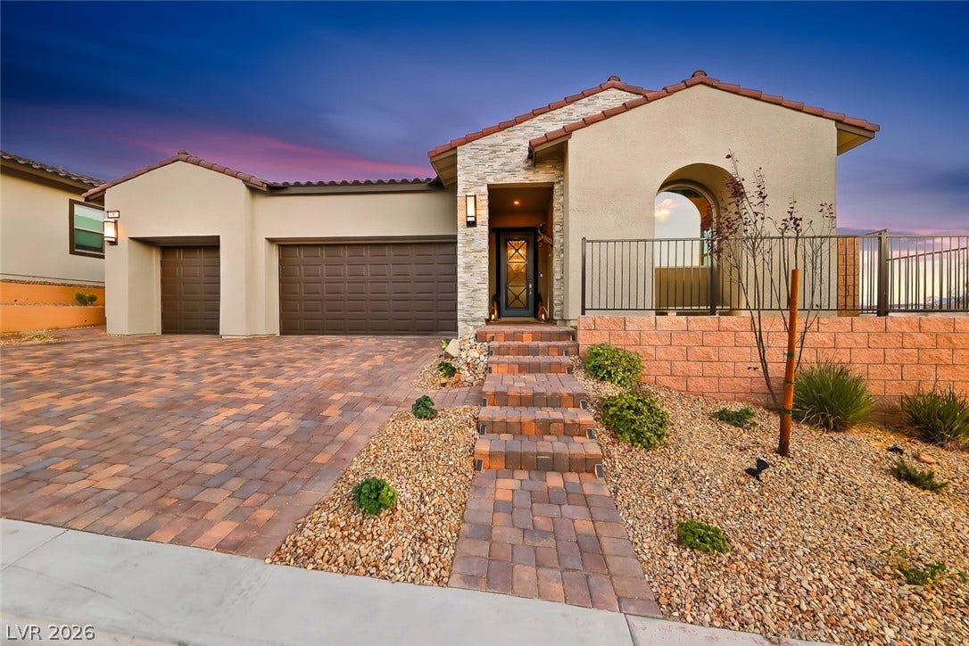 Stone accents and a paver driveway introduce this modern single-story desert home.