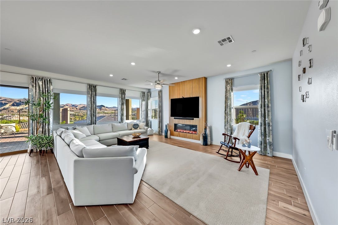 Gleaming wood-look floors, tall windows, and a modern fireplace wall elevate this bright living area.
