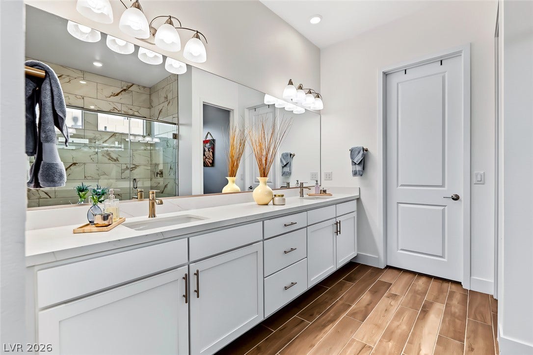 Rich wood-look tile flooring and a lengthy quartz-topped vanity define this modern bathroom.