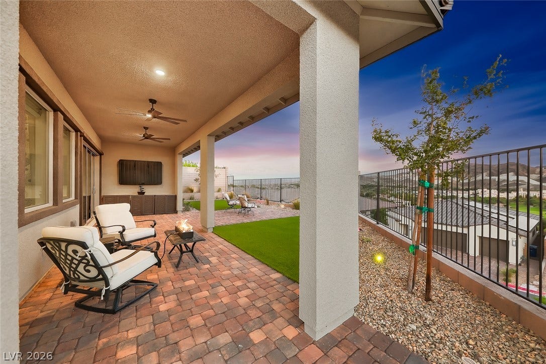 An inviting covered patio features warm brick pavers and sweeping neighborhood and mountain views.