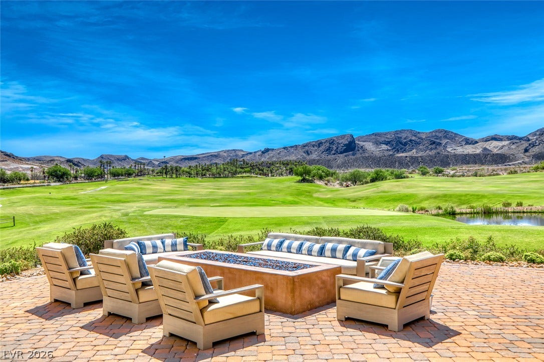 A spacious brick patio overlooks a lush green golf course and distant mountain ranges.