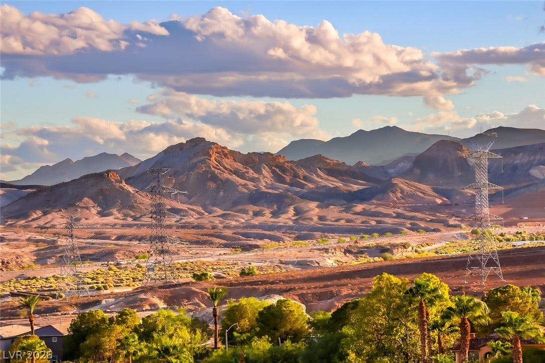 Dramatic mountain vistas rise above the desert landscape under a cloud-filled sky.