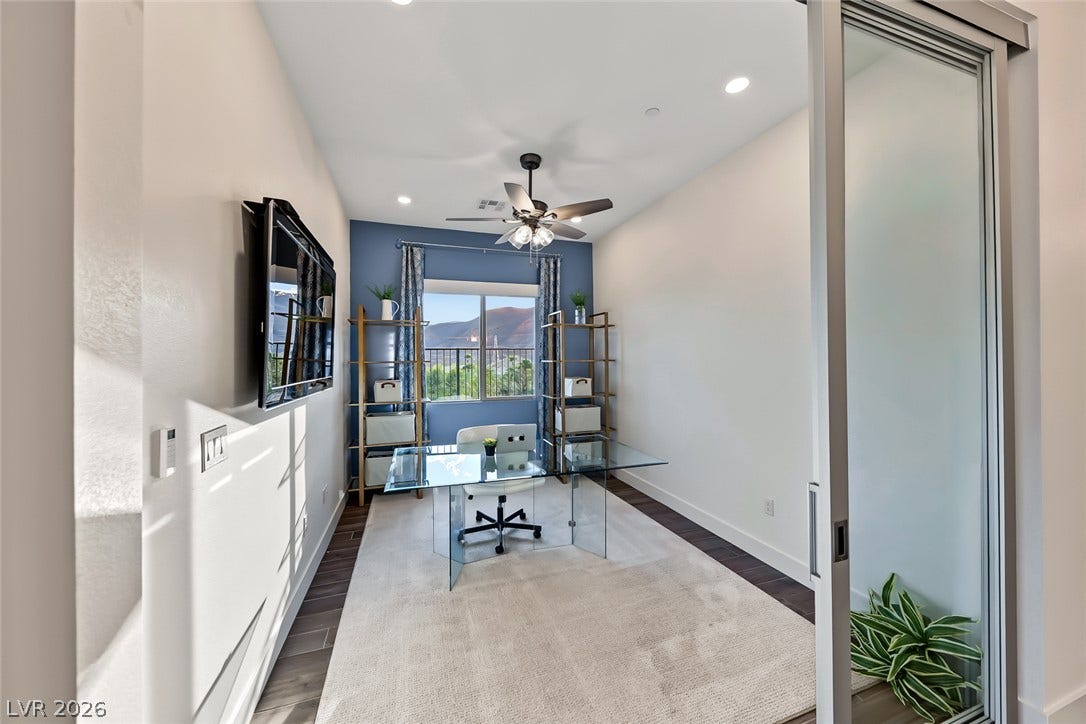 A glass sliding door opens to a dedicated home workspace featuring recessed lighting and wood floors.
