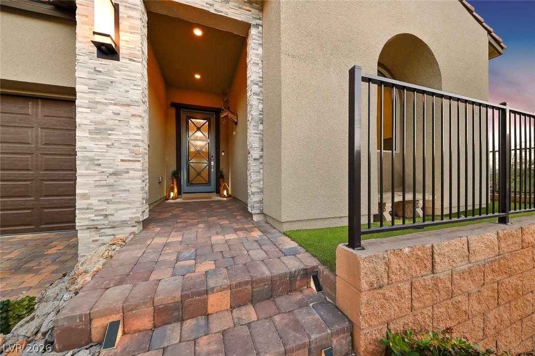 An inviting stone-accented entryway features a warm paver walkway leading to the front door.