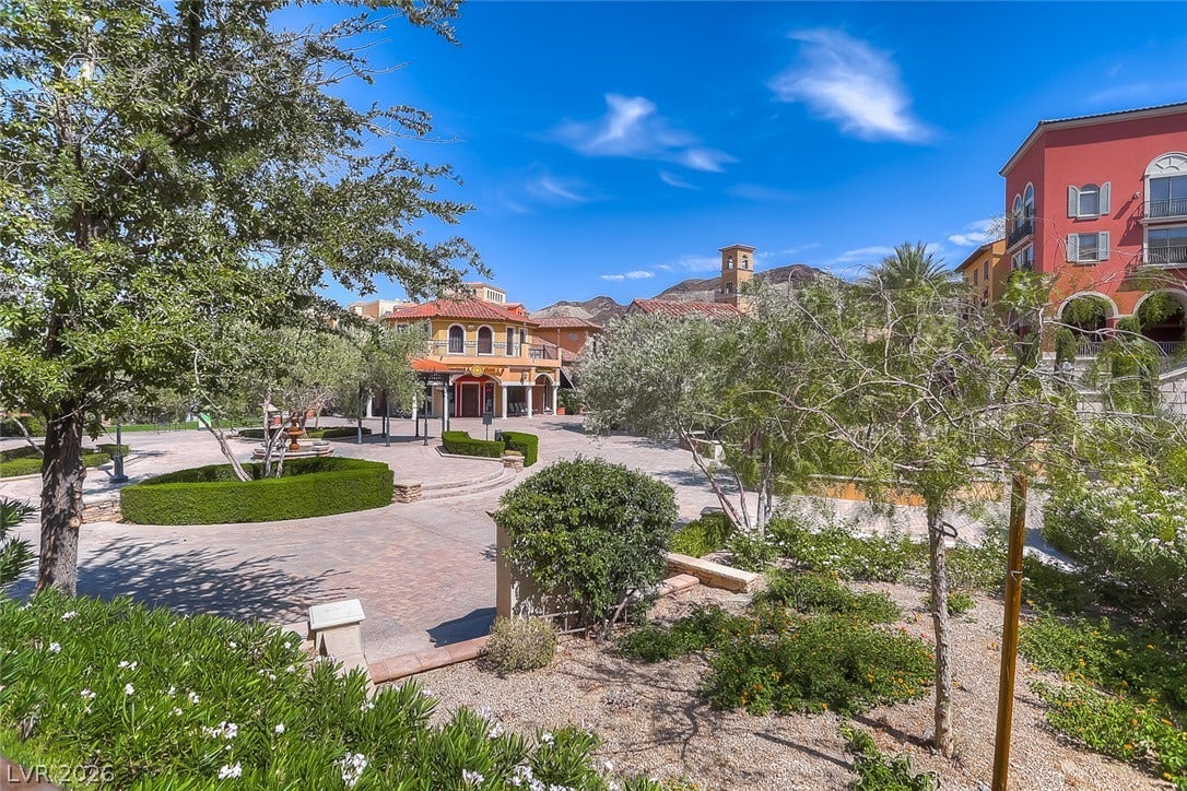 Mediterranean-inspired architecture frames a beautifully landscaped stone courtyard under clear blue skies.