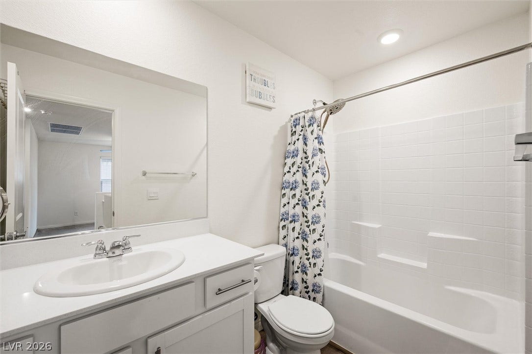 5651 Scarlet Rock Street, North Las Vegas, NV 89081 A clean tiled tub shower combination and solid vanity space define this bathroom.