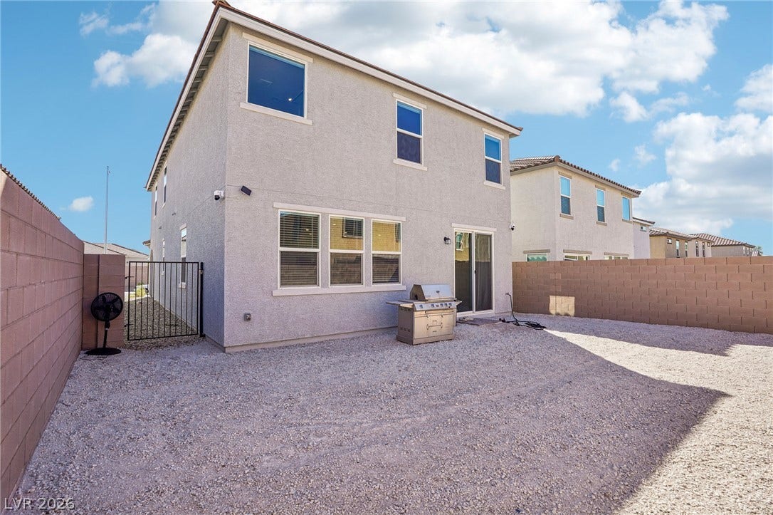 5937 Violet Crown Street, North Las Vegas, NV 89081 An enclosed backyard features gravel ground cover, a privacy wall, and stucco exterior walls.