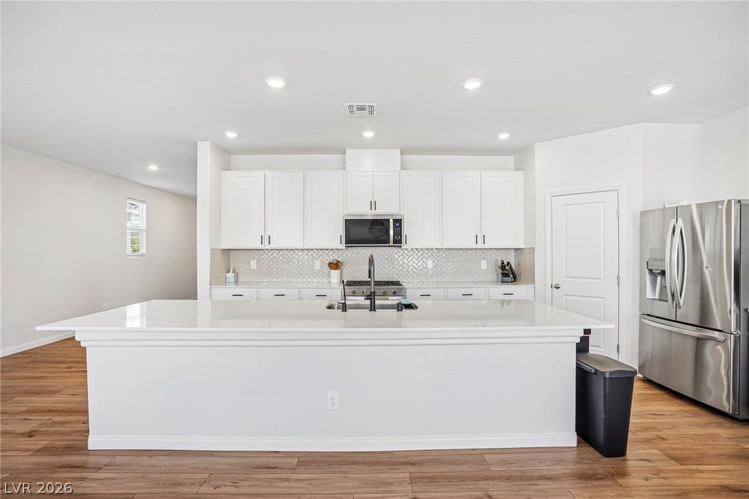 5937 Violet Crown Street, North Las Vegas, NV 89081 An expansive central island grounds this contemporary culinary space over rich wood-style flooring.
