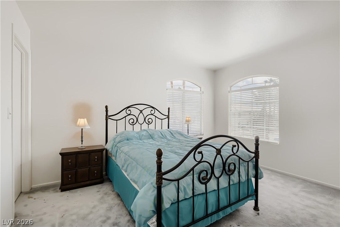 Arched windows invite natural light to illuminate this carpeted bedroom.