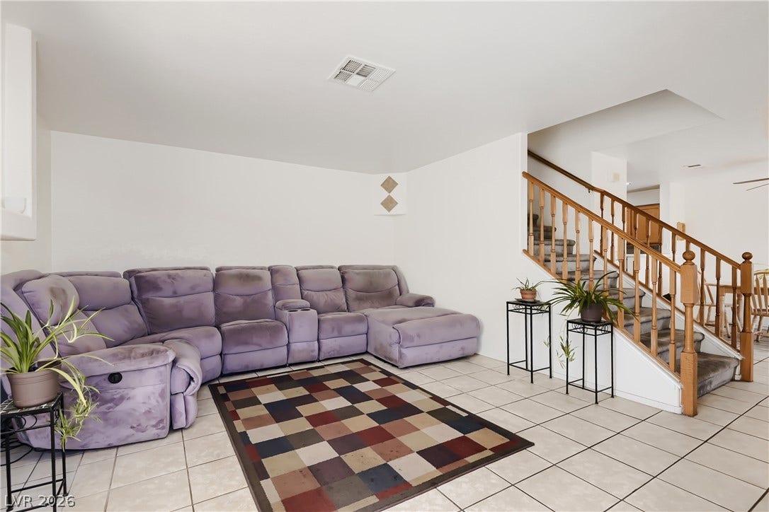Tiled flooring and a classic wooden staircase define this comfortable living area.